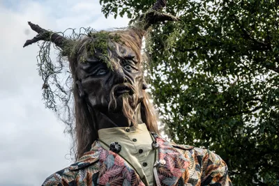 Una figura del bosque, de cara oscura, con cuernos de rama y musgo colgando, recortada contra el cielo.