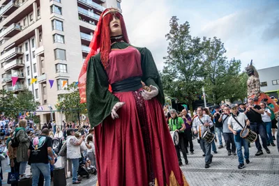 La giganta pelirroja avanza por la calle con la gente alrededor y los tamborileros detrás.