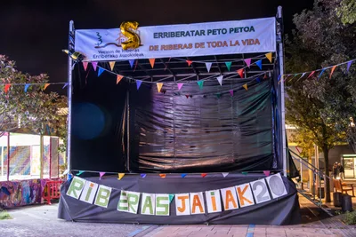 El escenario de noche, iluminado, con la pancarta «Erriberatar peto petoa · De Riberas de toda la vida» y las letras de «Riberas Jaiak 20».