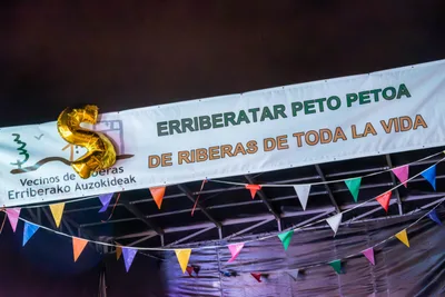 La pancarta de la asociación con un «20» de globos dorados encima y banderines debajo.