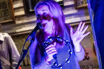 Nagore Fernández, la voz de Radio Rebelde, canta con una pandereta bajo una luz morada.