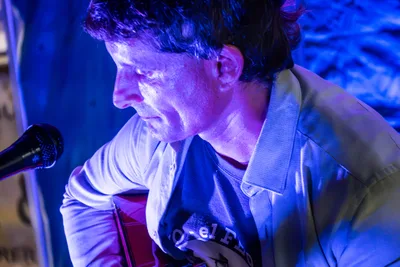 Xabi Mendiluze, el guitarrista de Radio Rebelde, mira las cuerdas bajo una luz azul.