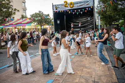 Chavalas bailando delante del escenario, con el «20» de globos dorados encima.