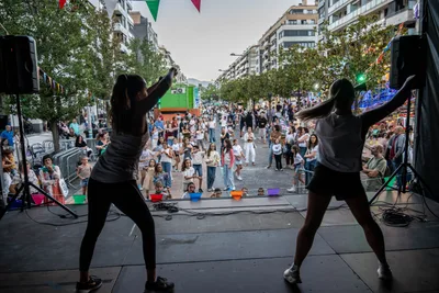 Desde el escenario, dos monitoras de zumba de espaldas y a contraluz bailan frente a la avenida llena, que las sigue.