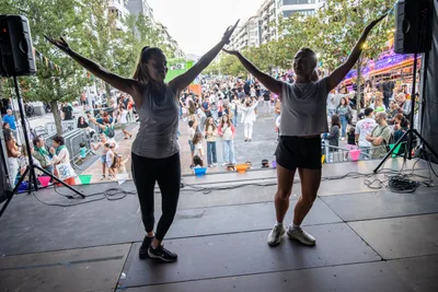 Las dos monitoras de zumba con los brazos en alto al final de un baile, y la avenida delante.