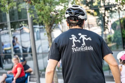Un monitor de Patin Eskola de espaldas, con casco blanco y el logotipo de la escuela en la camiseta.