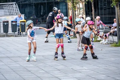 Una fila de niñas patina de la mano por la plaza.