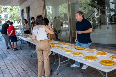 La mesa larga de las tortillas bajo los soportales, con vecinos mirándolas de pie.