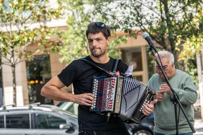 El acordeonista toca la trikitixa mientras un señor mayor lo mira desde detrás.