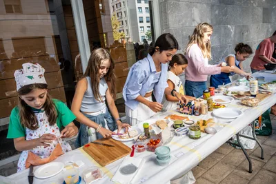 Varios niños preparan pintxos a la vez; una niña lleva gorro de cocinero.