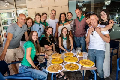 Una cuadrilla posa en un bar alrededor de una mesa llena de tortillas, varios con el pañuelo verde.