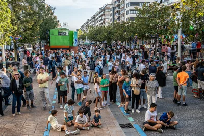 La avenida llena delante del escenario, con niños sentados en el suelo en primera fila.