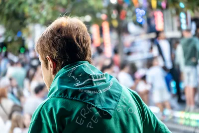 De espaldas, un hombre con el pañuelo verde de las fiestas mira al público desde el escenario.