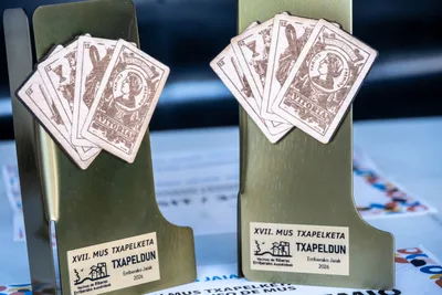 Los trofeos del torneo de mus, dorados y con naipes de madera pegados.