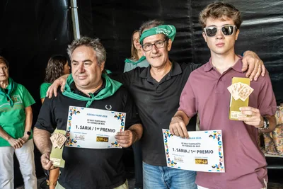Los ganadores del torneo de mus con el diploma del primer premio y sus trofeos de naipes.