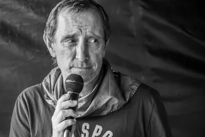 En blanco y negro, el presentador con el micrófono pegado a la boca.