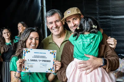 El primer premio del concurso fotográfico: una mujer con el diploma y un hombre con una niña en brazos.