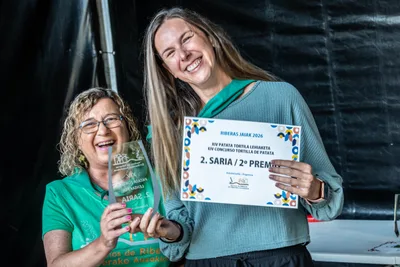 Una mujer de la comisión entrega el trofeo del segundo premio de tortilla a una ganadora que se ríe con el diploma.