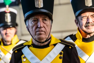 Un gastador mayor de frente, con la casaca marrón y amarilla y el chacó puesto, entre otros dos.