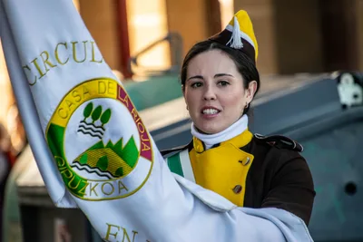 Una cantinera lleva la bandera de la sociedad, con el escudo de la Casa de La Rioja en Gipuzkoa bordado.