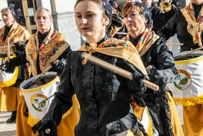 Una mujer joven con mantón amarillo toca el tambor dentro de la formación.