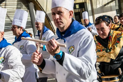 Un cocinero toca con las baquetas cruzadas, rodeado de mantones y gorros blancos.