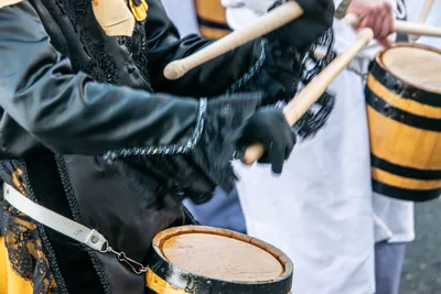 Detalle de unas manos enguantadas de negro tocando el barril con las baquetas.