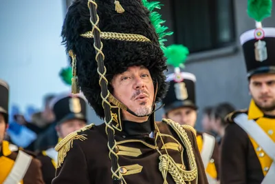 El tambor mayor con el gorro de piel negro, los alamares dorados y el bastón de mando.