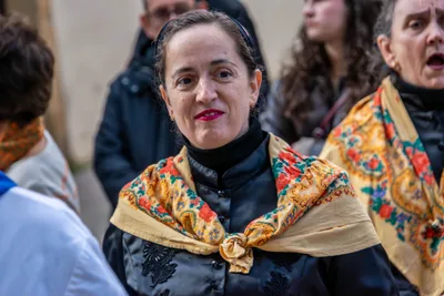 Retrato de una mujer con mantón amarillo de flores, mirando a la cámara entre la formación.