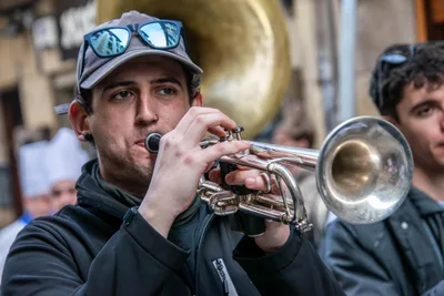 Un trompetista de la banda toca con gorra y gafas de sol subidas a la visera.