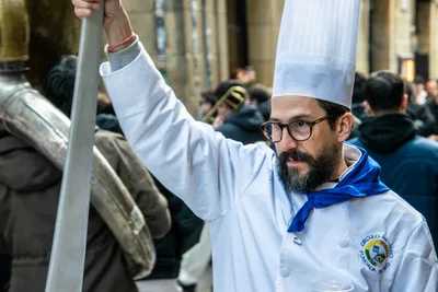 Un cocinero con gafas levanta la pala de cocina; en la chaquetilla, el escudo del Círculo Riojano.