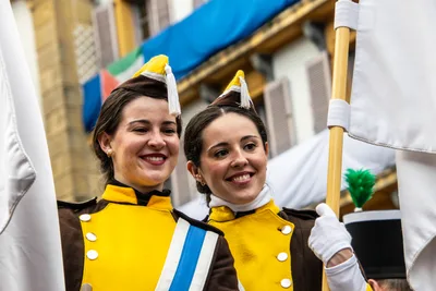 Dos cantineras sonríen juntas con el chacó amarillo y la banda cruzada.