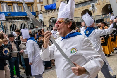 Un cocinero con gafas rojas blande la cuchilla mientras cruza la plaza.
