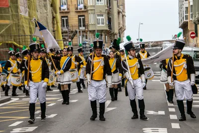 La compañía baja una avenida ancha: gastadores, cantineras y las banderas por delante.