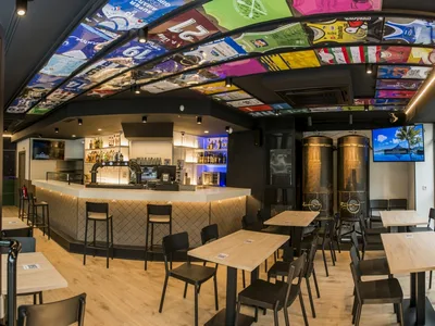 Campus Ondarreta: barra blanca, dos tanques de cerveza junto a las mesas y un techo forrado de camisetas de fútbol.